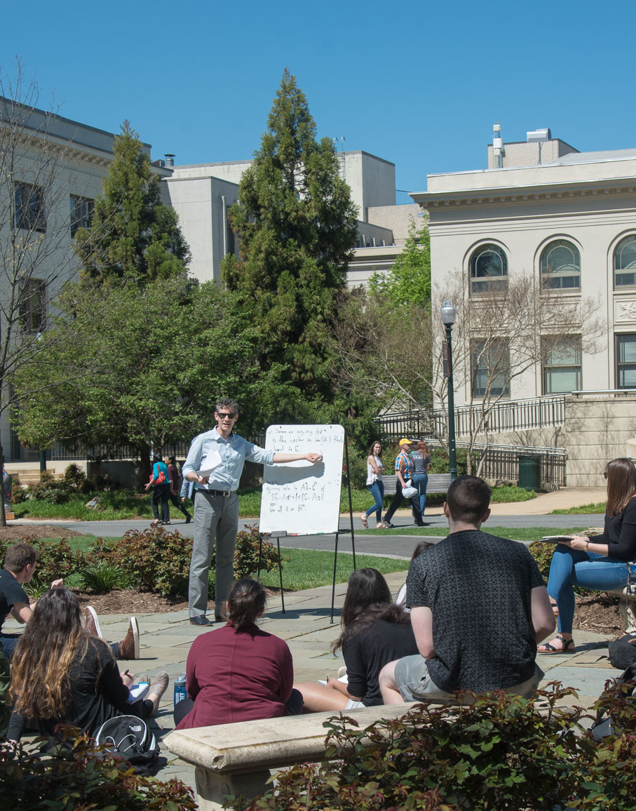 D17_530_013_crop_v A professor conducts a class discussion outside on the quad on a beautiful sunny day.