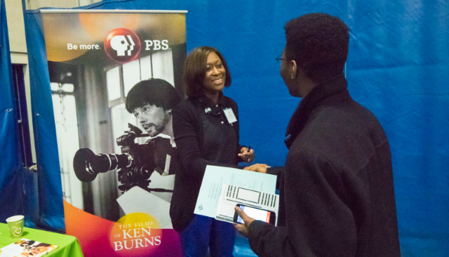 A PBS representative shakes hands with an AU student at the Job & Internship Fair