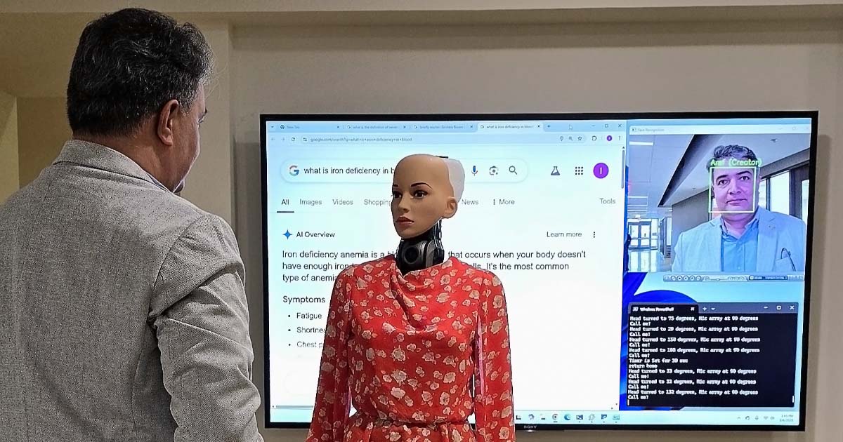 Iris explaining iron deficiency to creator Aref Zahed. Iris' face is turned towards Aref and her processing — facial recognition and a Google search — is shown on a monitor