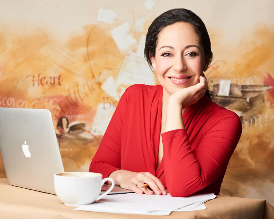 Jennifer Hamady seated with a laptop and coffee cup
