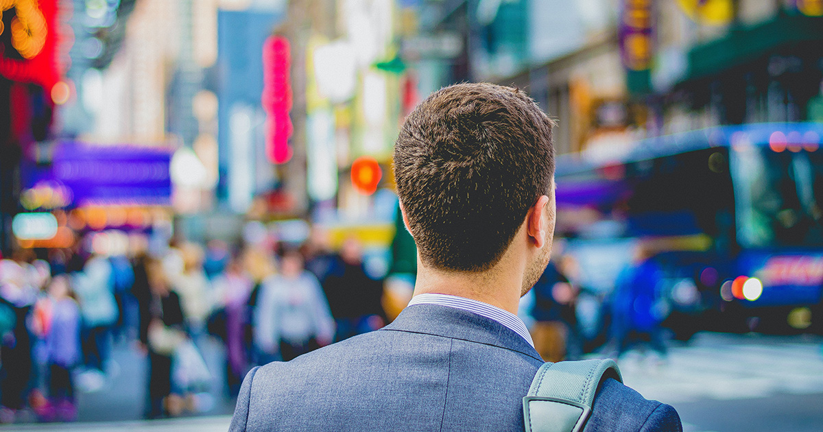 A person in a suit walking in the street. Photo by Saulo Mohana