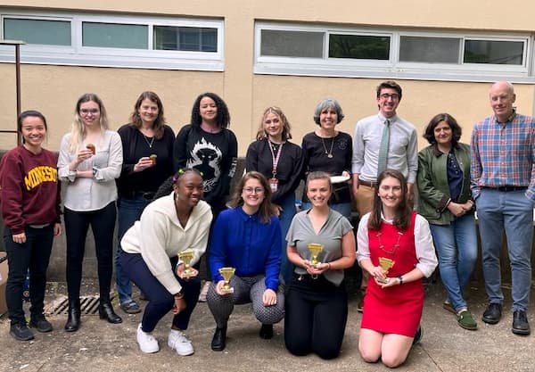 Psychology faculty and students in a courtyard with awards.