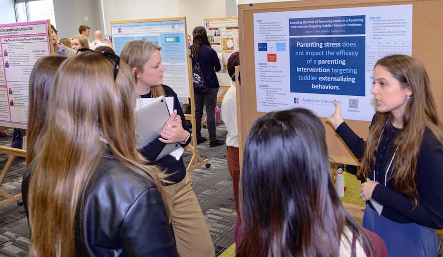 Student discussing poster with attendees.