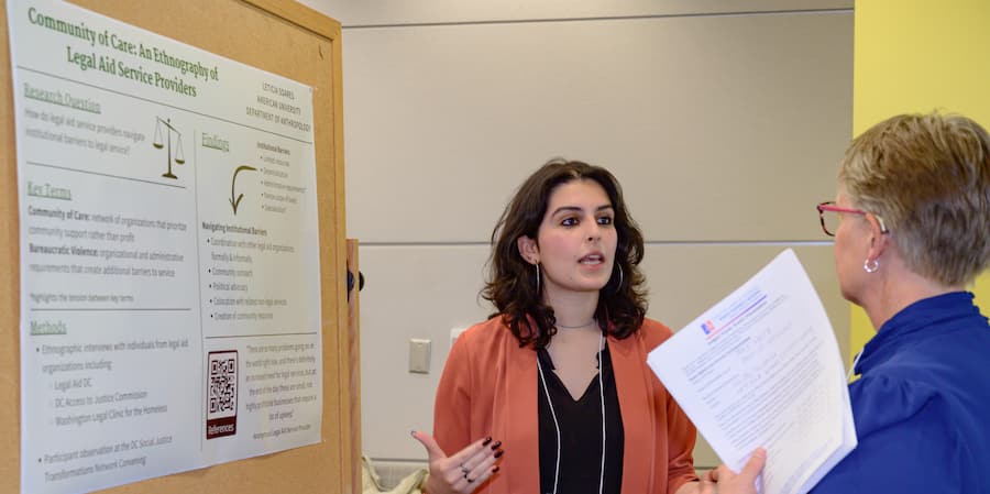 Anthropology gradudate student discussing poster with faculty.