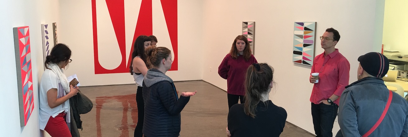Students in a gallery space with paintings on the walls