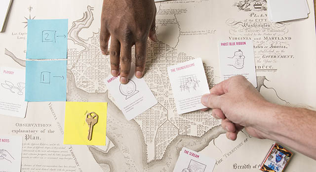Students' hands working on a game over a map of Washington, DC