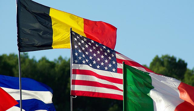Cuban, Belgian, American, and Italian flags, with sky as background