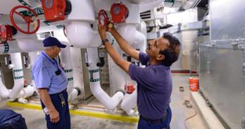Facilities Management staff check the equipment of the new chiller in the basement of McDowell. Photo by Jeff Watts.