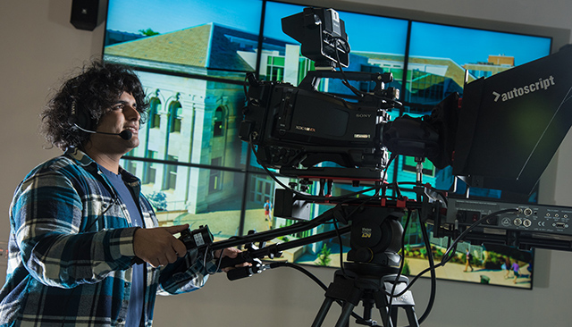 A young man works the studio camera in the School of Communication