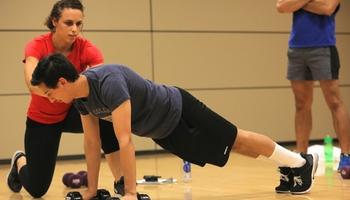 Personal trainer overseeing client doing push ups.