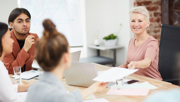 Older woman handing paper to a younger woman