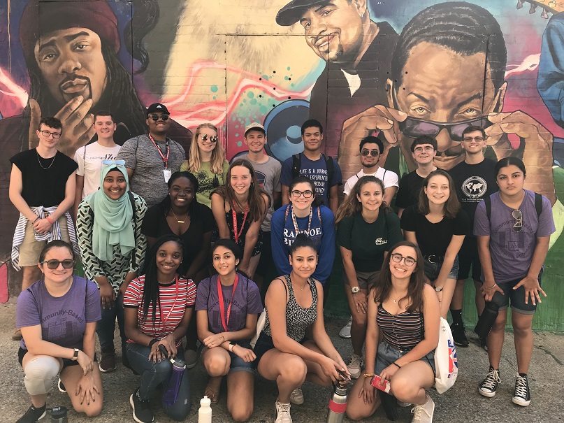 Students pose in front of mural