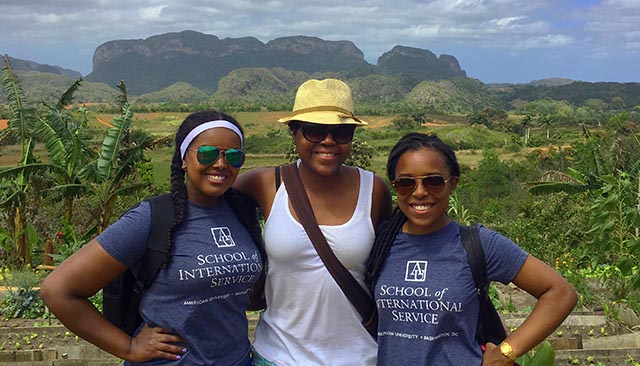 three girls with School of International Service shirts with hilly terrain