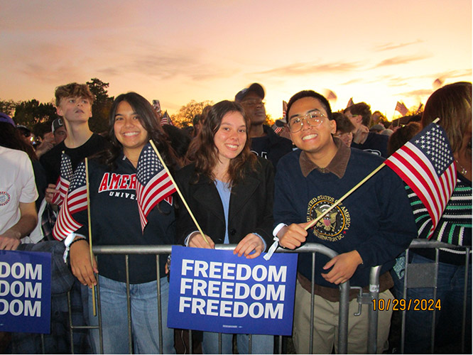 3 students pose at the gate with American flags and a Freedom sign at the Kamala Harris for President rally held on the National Mall 3 students pose at the gate with American flags and a Freedom sign at the Kamala Harris for President rally held on the National Mall