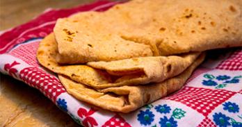 close up of the leavened flatbread, roti on a plate with a checkered napkin