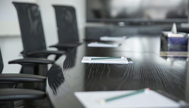 empty chairs at a conference table set with paper and pens