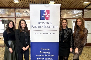 four women speakers standing around a poster