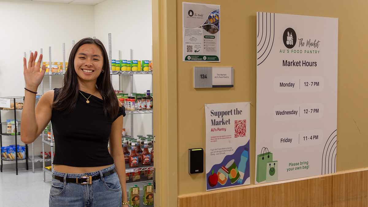 A student stands in the doorway of the Market, waving to the camera.