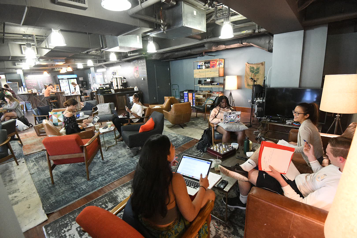 Students gathered together on the couches in the bridge and studying.