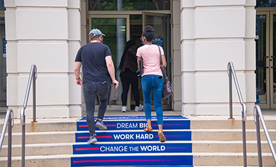 New student and her dad walk up the steps into orientation