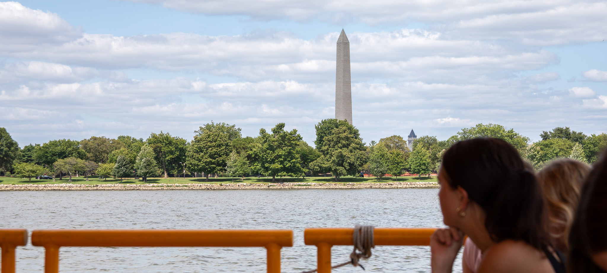 A student looks from a boat to the Washington Monument in the distance.