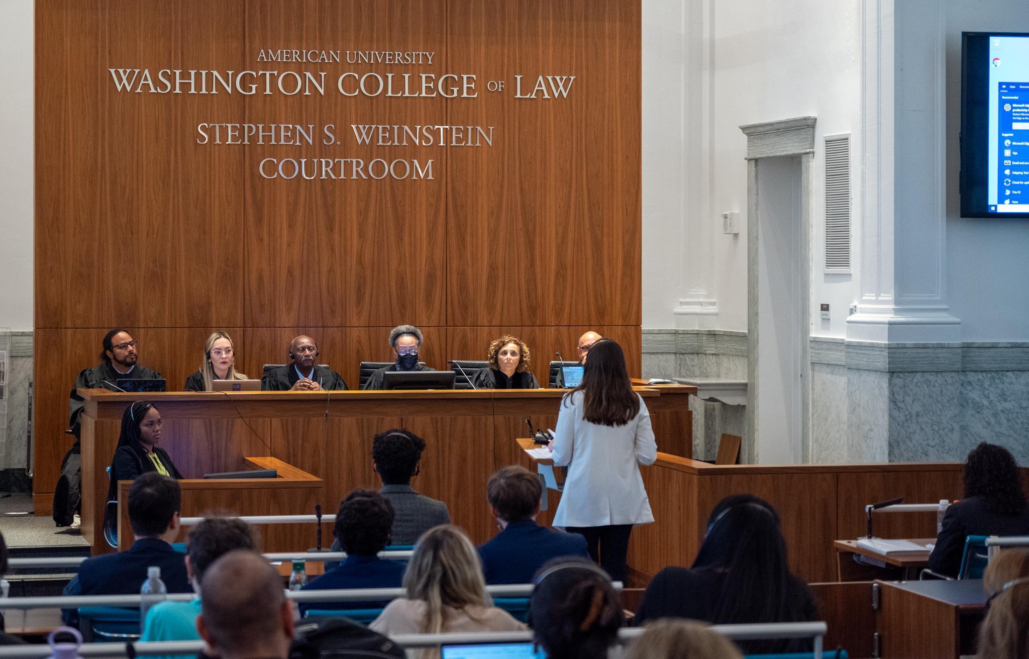 Judges and students listen as a participant argues their case. Judges and students listen as a participant argues their case.